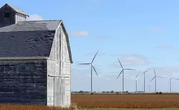 a barn in front of wind turbines