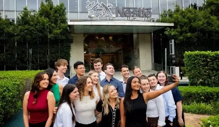 Group of young adults taking a selfie outside a Nestlé building.