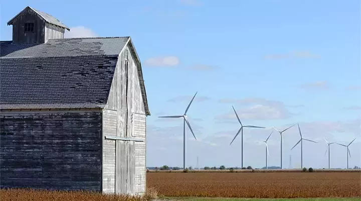 Arable fields with wooden barn and wind turbines in distance